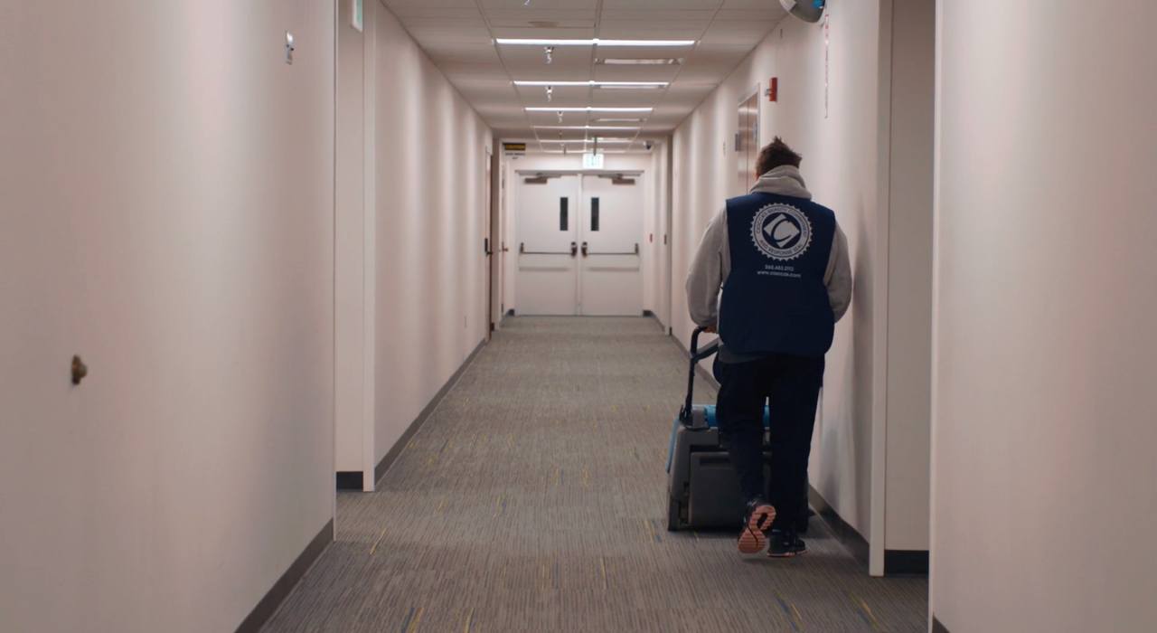 Ciocca employee using industrial vacuum down empty hallway in office Ciocca employee using industrial vacuum down empty hallway in office