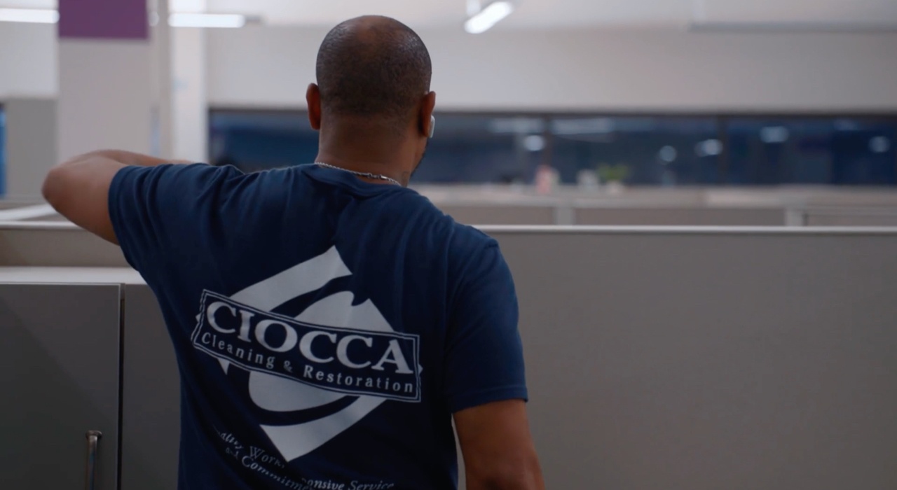 Ciocca employee wearing shirt with Ciocca logo while dusting office cubicle Ciocca employee wearing shirt with Ciocca logo while dusting office cubicle